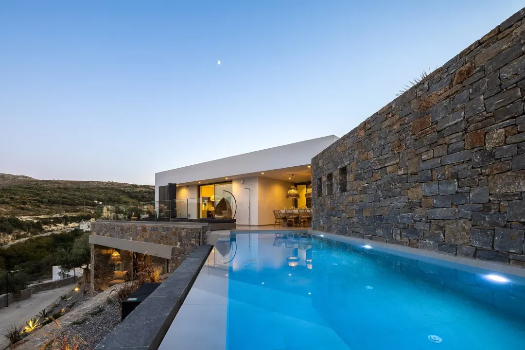 Villa ANDRIOTIS mit beleuchtetem Infinity-Pool in der Abenddämmerung